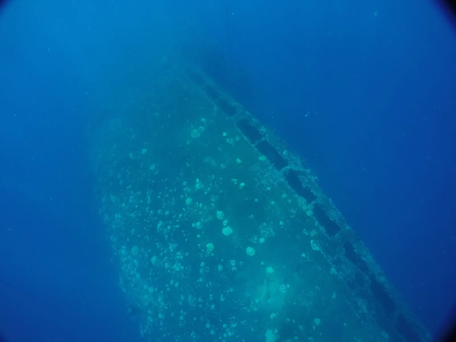 The hull of the Rio de Janeiro Maru lying on its side in blue water, Chuuk Lagoon